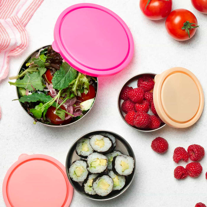 Rise collection of ever eco round nesting containers styled on a kitchen bench filled with salad, sushi and raspberries with the coloured lids next to each.