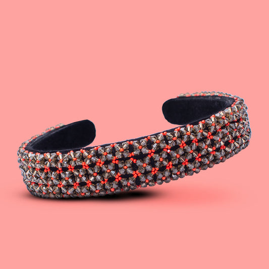 Decorative headband with red and silver pattern on a pink background